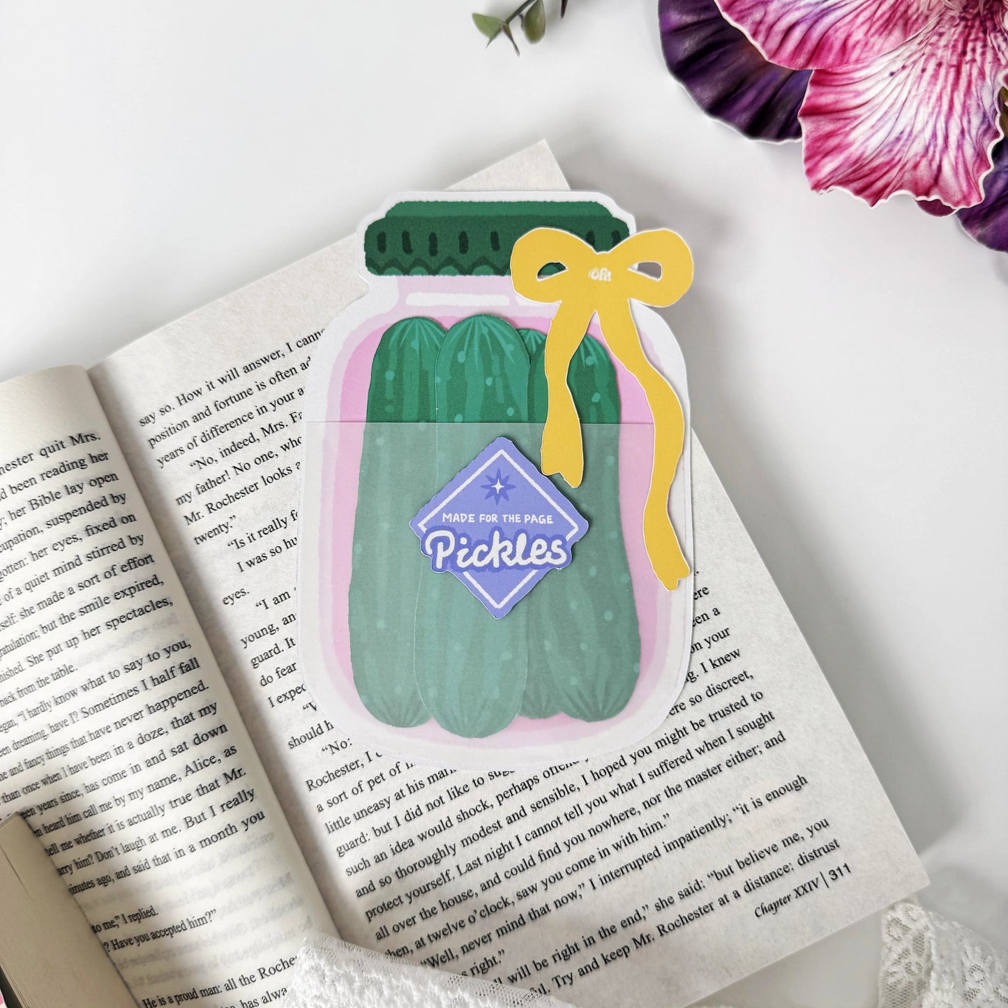 Pickle Jar Bookmark Set displayed on an open book with four green cucumber bookmarks tucked inside the pink jar holder