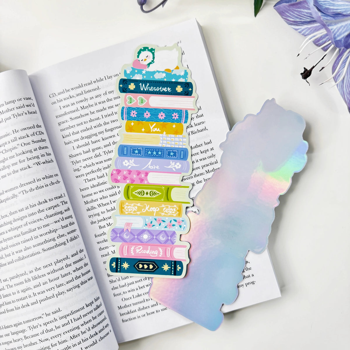 Front and silver holographic back of the Wherever You Are book stack classic bookmark on an open book