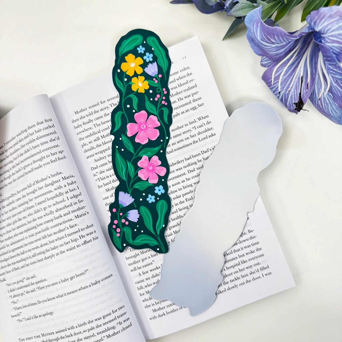 Front and silver holographic back of the Garden in Bloom classic bookmark on an open book