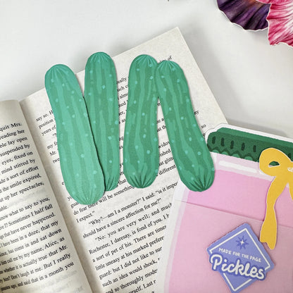 Four removable green cucumber bookmarks beside the pink Pickle Jar holder on an open book