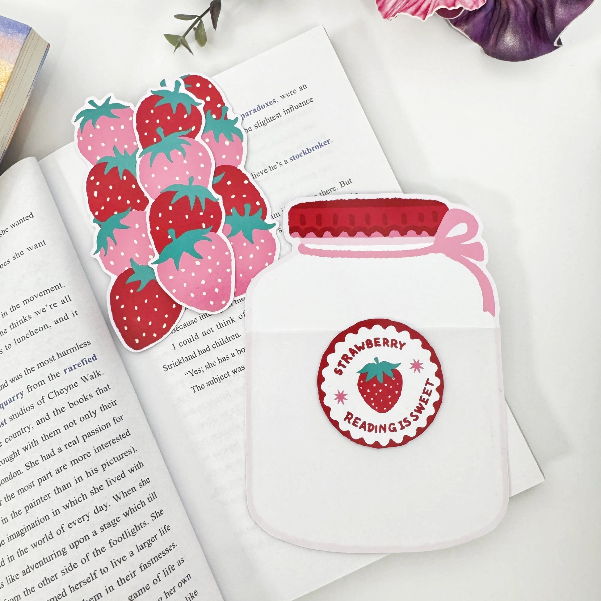 Three strawberry bookmarks removed and arranged beside the empty Strawberry Jar holder on an open book