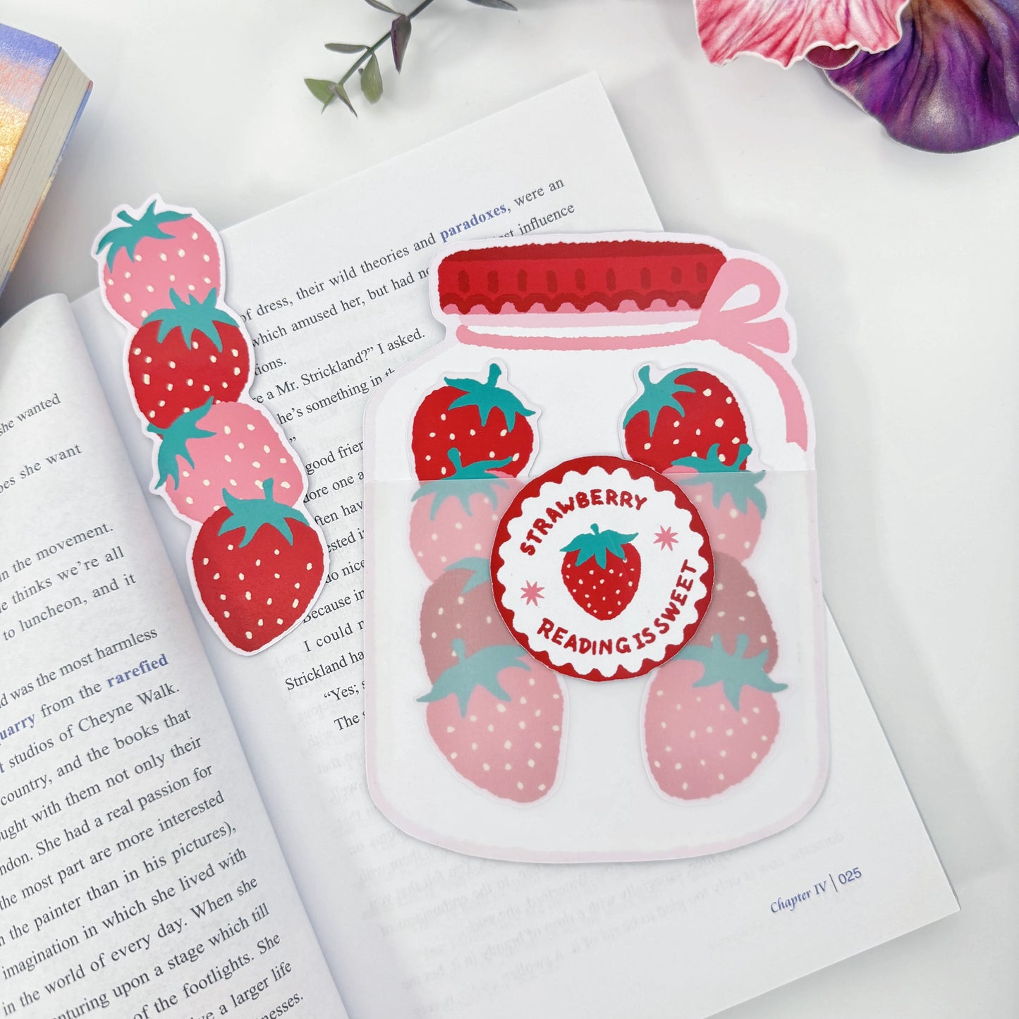 One strawberry bookmark removed beside the jar holder, with two bookmarks remaining inside on an open book